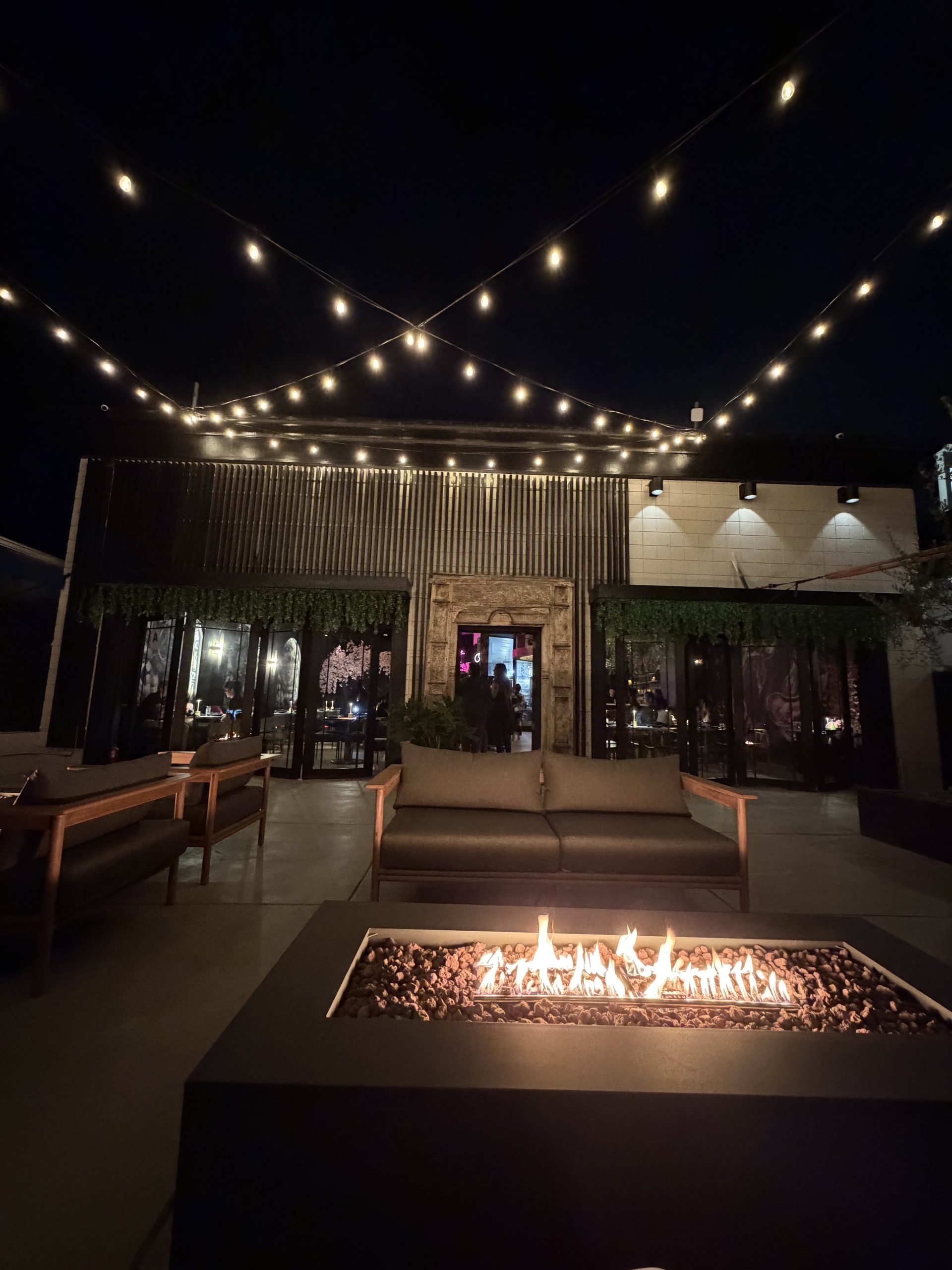 Cherryfish patio at night with fire pit, lounge seating, and string lights at private event venue in Pacific Beach San Diego