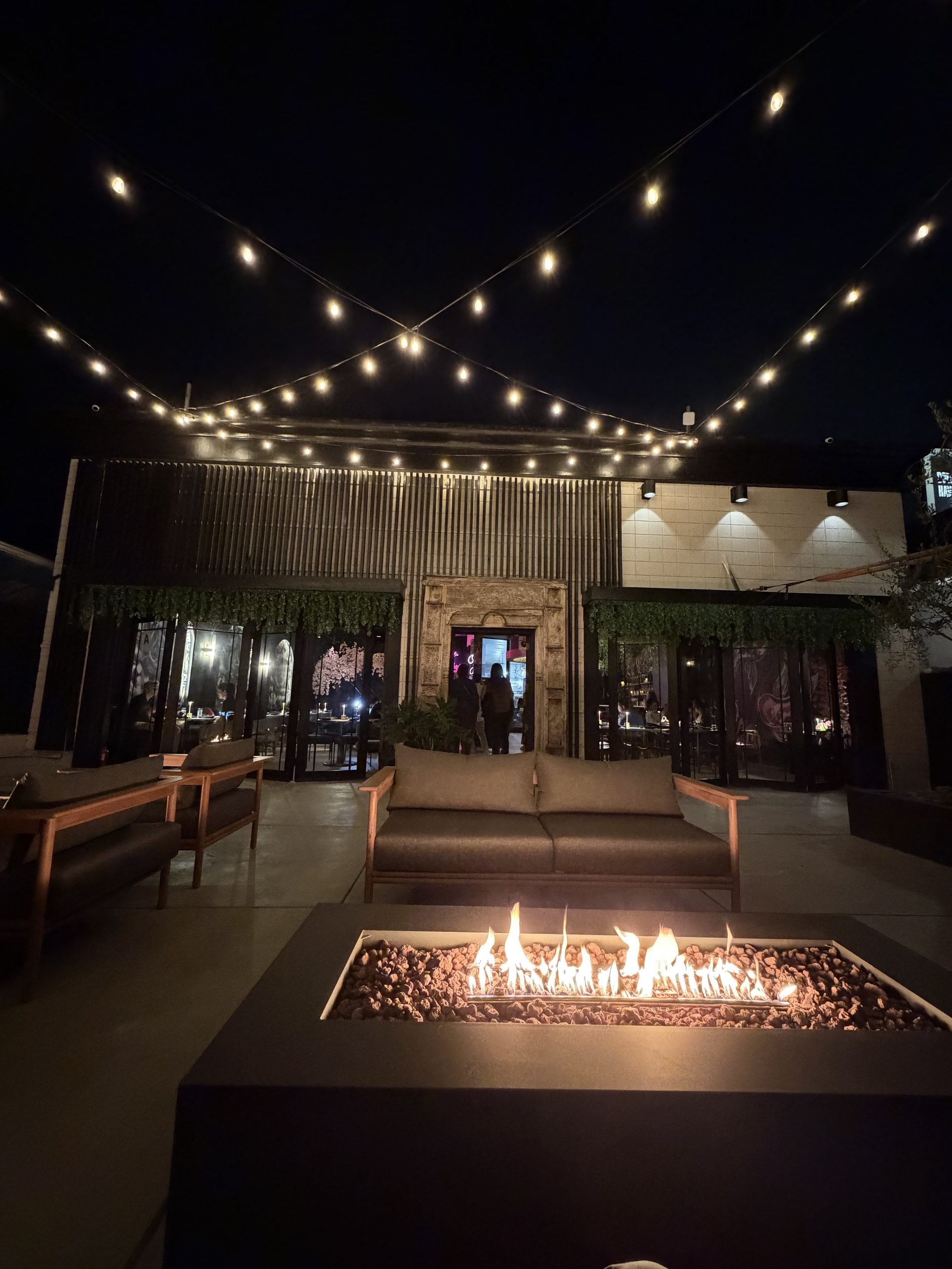 Cherryfish private event patio with fire pits, mid-century lounge seating, and ornate stone-framed entry in Pacific Beach San Diego