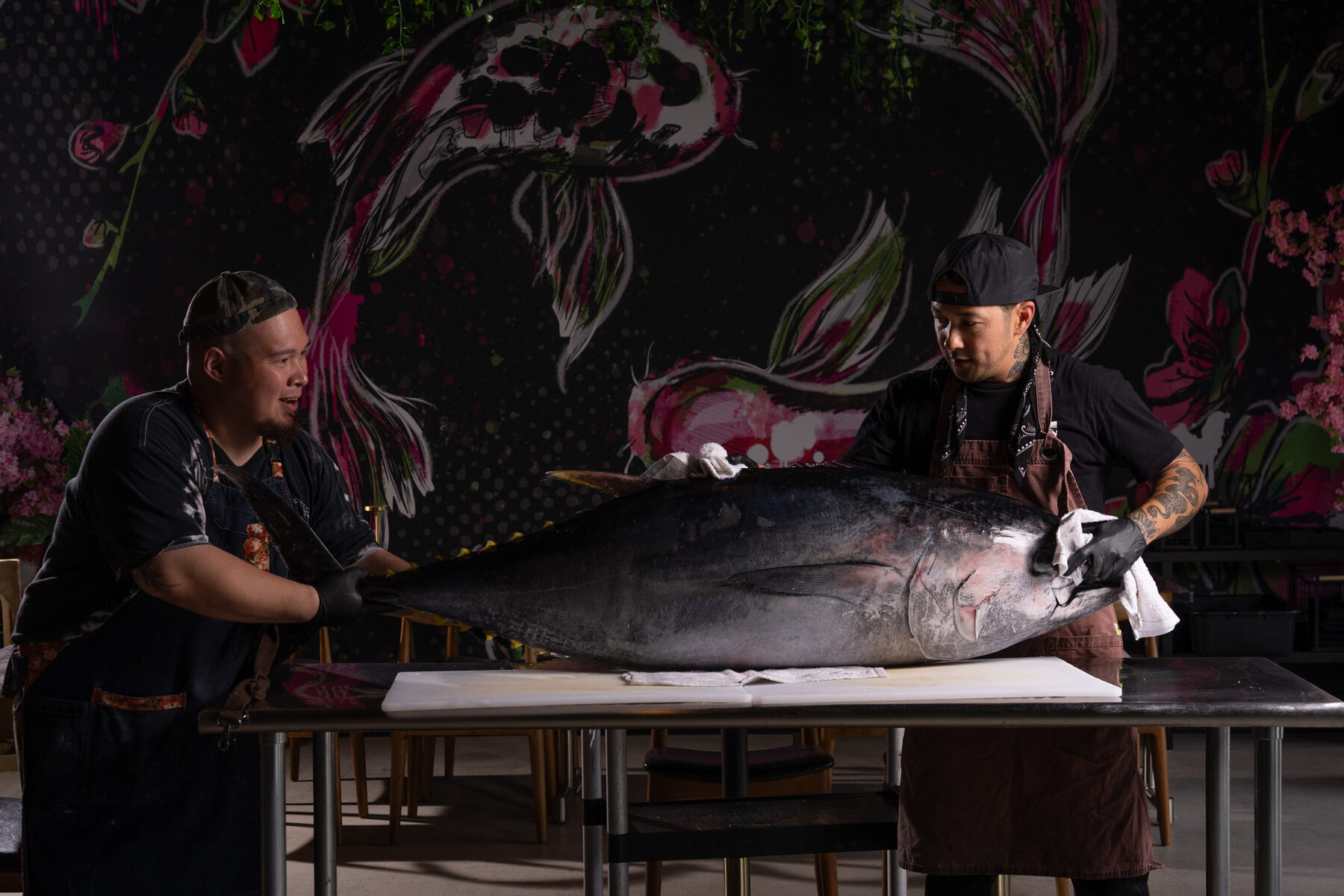 Two Cherryfish chefs breaking down a whole bluefin tuna in the dining room beneath the custom koi mural in Pacific Beach San Diego